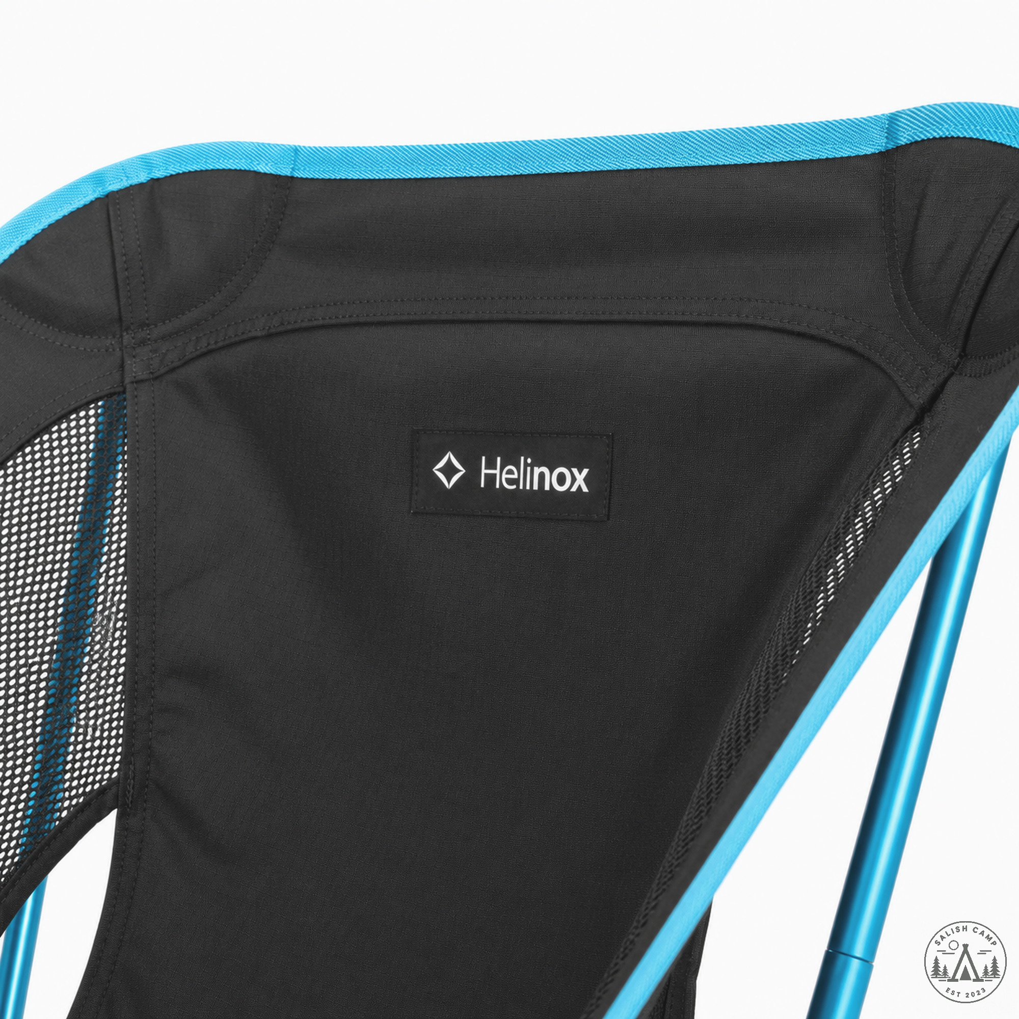 Close-up of the small Helinox tab on the upper back of the Black Chair One (re), below cyan binding