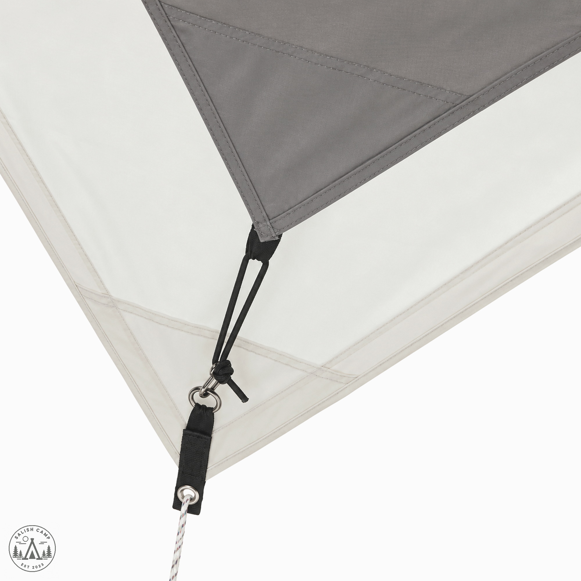 Grey triangular corner of the hexa against ivory fabric, with black cord, metal rings, and a guyline