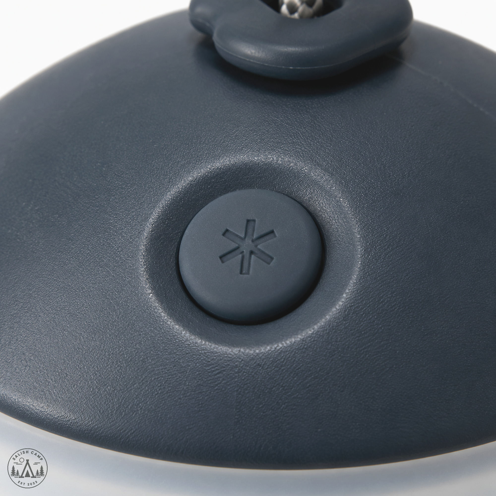 Close-up of the round power button on the dark Night Sky cap