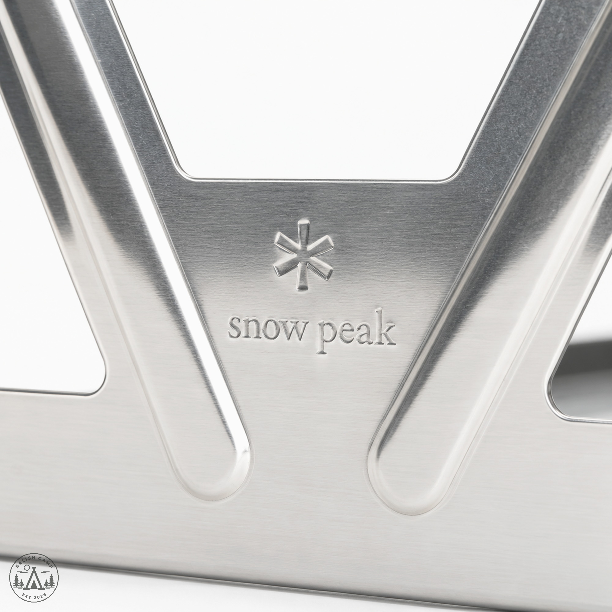 Close-up of a stamped asterisk and lowercase snow peak on brushed stainless