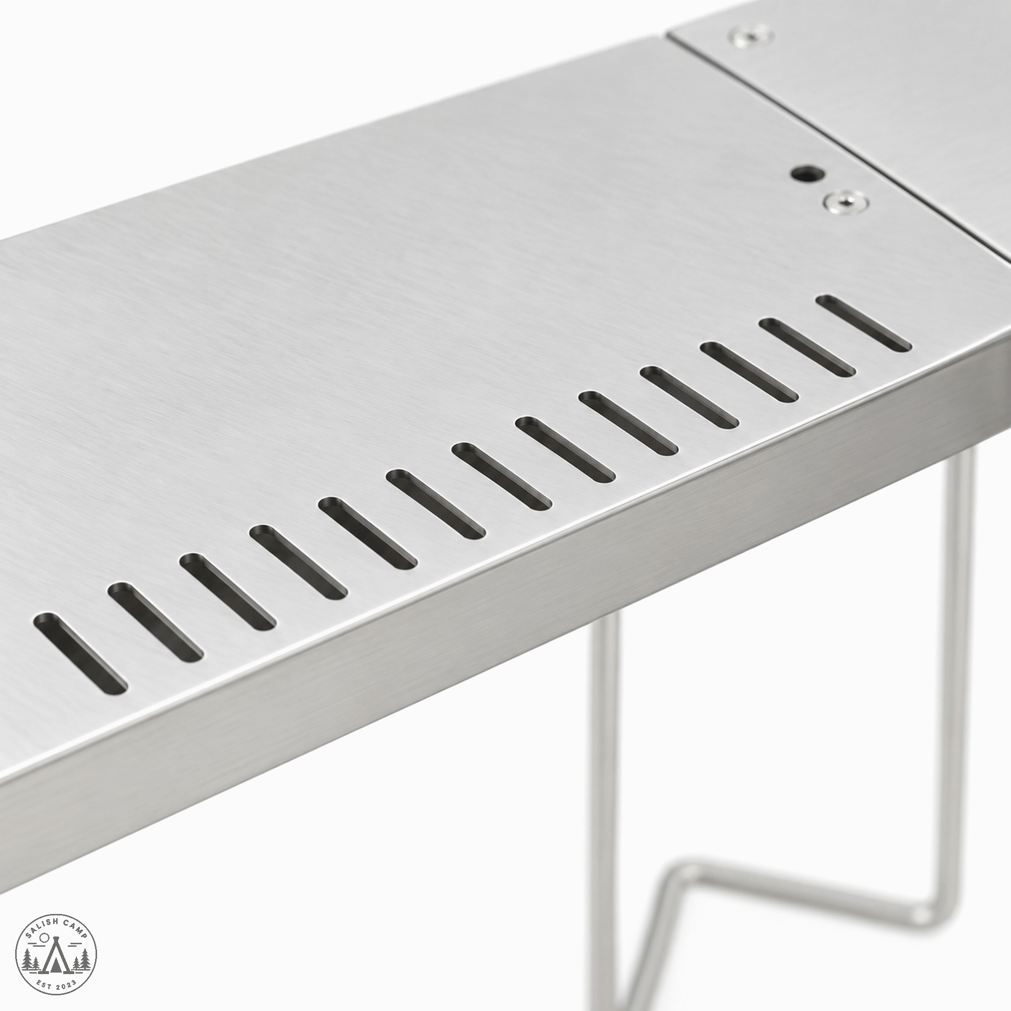 Close-up of elongated slots along the inner edge of one Jikaro stainless tabletop